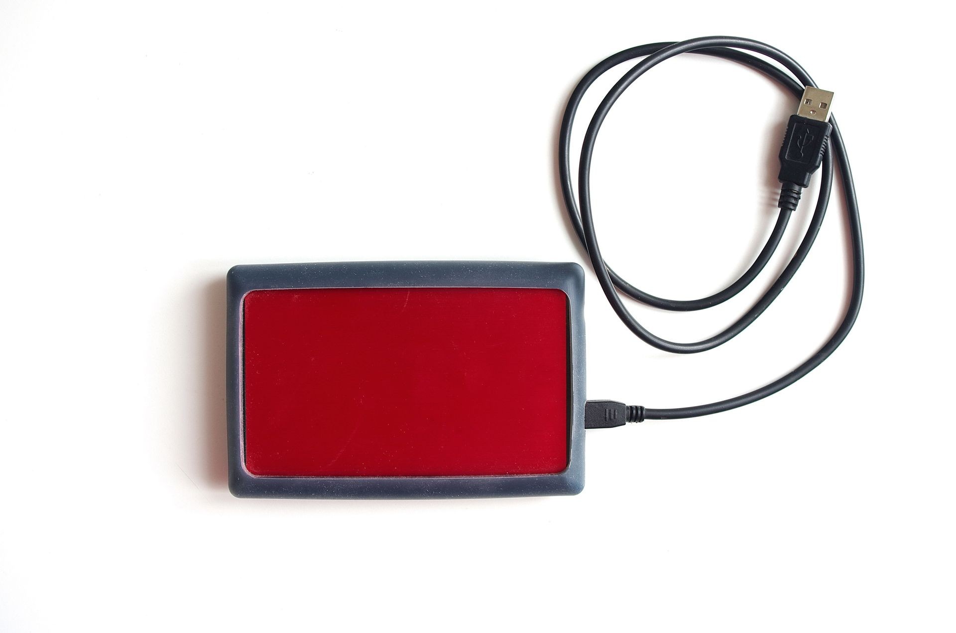 Red external hard drive with usb cable.
